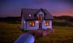 Person holding a model house representing ownership